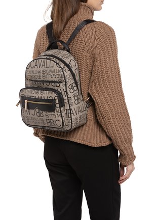 Sac à dos noir et beige en tissu avec impression de logo, comprenant deux compartiments zippés, des bretelles ajustables et un extérieur texturé.