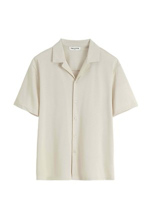 Chemise beige à manches courtes boutonnée, col camp, design minimaliste et étiquette de marque visible à l'intérieur de l'encolure.