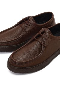 Zapatos de cuero marrón con un acabado texturizado, puntera redonda y cordones finos. Presentan un cuello acolchado y una suela de goma para mayor agarre.