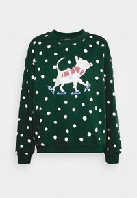 Suéter de color verde oscuro con lunares blancos y un gato blanco con una bufanda roja patinando sobre hielo con patines azules en el frente.