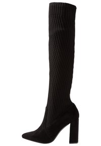 Bota de ante negro hasta la rodilla con tejido acanalado y punta afilada, y tacón ancho cuadrado. Parte superior texturizada con una sección de puntera lisa.