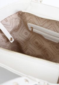 Borsa a mano bianca con esterno testurizzato, hardware dorato e fodera interna beige a motivo con logo "CAFENOIR". Include una tasca con zip.