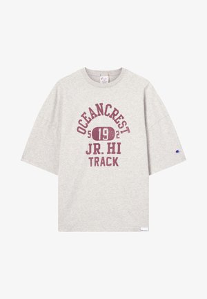 Helles graues T-Shirt mit kurzen Ärmeln, auf dem vorne in burgunderfarbenem Text "OCEANCREST 192 JR. HI TRACK" steht, sowie einem kleinen Champion-Logo auf dem Ärmel und dem Saum.