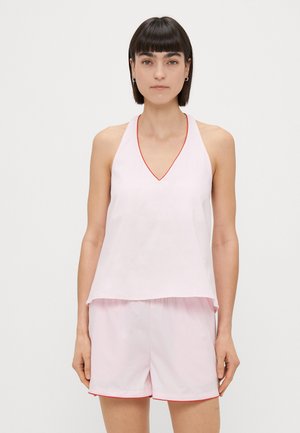 Rožinė beužkarda su V formos iškirpte ir raudonu apvadu, derinama su rožinėmis šortais, kurių apatinėje dalyje taip pat yra raudonas akcentas.