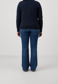 Jeans blu a zampa in denim, con un classico design a cinque tasche e cuciture a contrasto; la vista posteriore mette in risalto la cintura e le tasche.