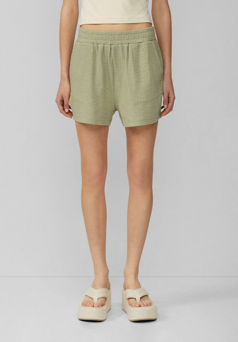 Lichtgroene korte broek met textuur en een elastische tailleband, met een losse pasvorm en zakken, gecombineerd met beige platform sandalen.