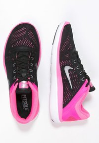 Scarpe sportive nere con tomaia in mesh traspirante e dettagli rosa, intersuola bianca e lacci neri. Logo Nike presente sul lato.