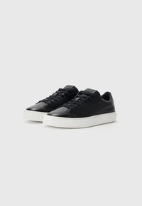 Sorte skinnesneakers med en glatt overflate, som har en hvit gummisåle, rund tå og flate snører. Pyntet med en logo på tungen.