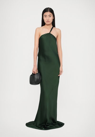 Rochie din satin verde cu o singură bretea pe umăr, textură moale și siluetă lungă și fluidă; asortată cu o geantă neagră, rotundă.