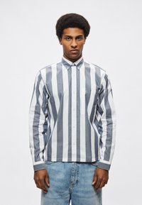 Πουκάμισο με κουμπιά και μακριά μανίκια που διαθέτει οριζόντιες ρίγες σε ναυτικό μπλε και λευκό, γιακά και τσέπη στο στήθος με κλασική εφαρμογή.