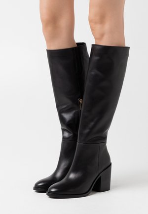 Botas de cuero negro hasta la rodilla con un tacón grueso y un acabado brillante, que cuentan con un zipper lateral y una textura suave.