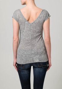 Grå kortärmad V-ringad t-shirt med en texturerad yta, figurnära passform och mjukt tyg, i kombination med mörkblå slim fit-jeans.