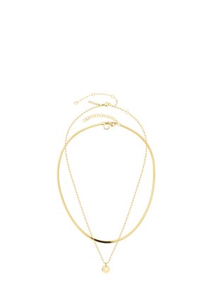 Deux colliers en or superposés, l’un épais et l’autre fin, avec un petit pendentif rond sur la chaîne plus fine, sur fond blanc.