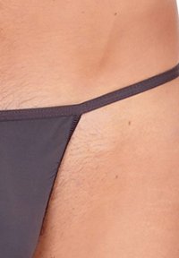 Schwarze Schwimmhose mit dünnen Seitenträgern. Der Stoff wirkt glatt mit einem matten Finish und minimaler Abdeckung. Ausgestattet mit sauberem Nähen.