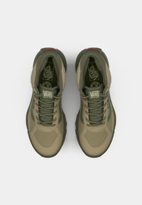 Olivengrønne Vans sneakers med en glat tekstur, der har forstærkede tåkapper, tykke såler og kontrasterende snørebånd.