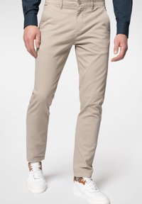 Beige chinos med slim fit, med klassiska fickor, en mjuk textur, och matchas med vita sneakers och en marinblå mönstrad skjorta.
