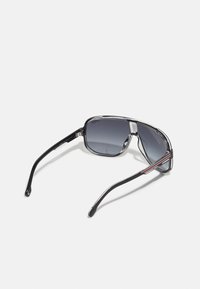 Mustad mustra paar pruunid raamid pruunide gradueeritud objektiividega, metallist aktsentidega ja voolujoonelise, ristkülikukujulise disainiga. Omab kõveraid käsi logodetailiga.