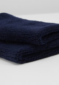 Cachecol de malha azul-marinho com uma textura suave, dobrado com um padrão de nervura consistente e bordas acabadas. Design compacto e versátil.