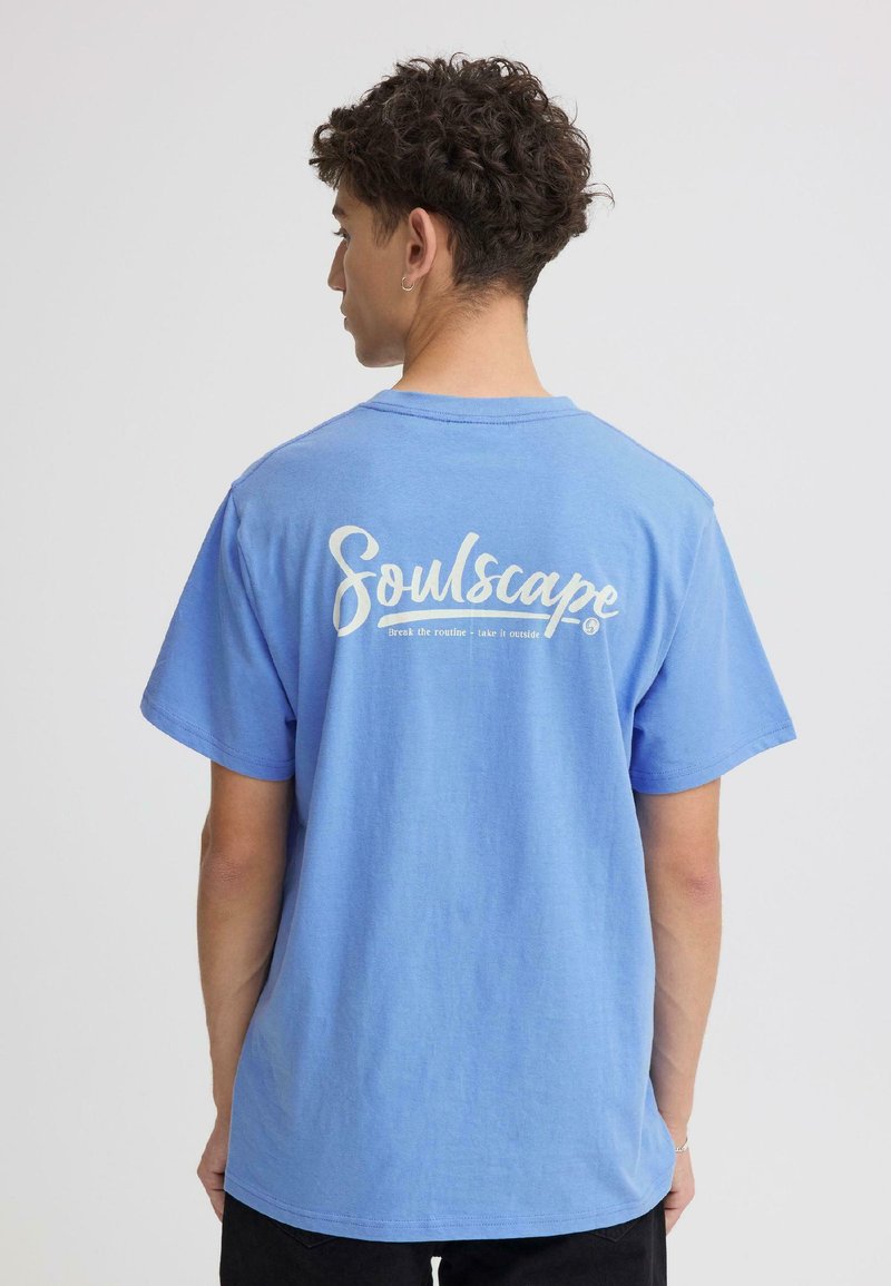 T-shirt en coton bleu avec un grand texte blanc "Soulscape" imprimé dans le dos. Manches courtes et coupe décontractée avec un col rond.