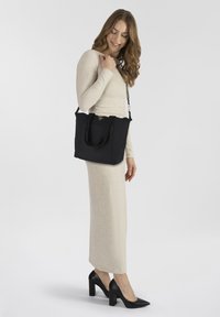 Borsa tote nera con due manici superiori, una texture in tessuto e un logo triangolare sul fronte. La borsa ha un design strutturato e una dimensione media.