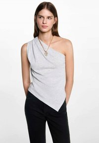 Asymmetrisk grå ærmeløs topp laget av mykt materiale, med drapert design og spiss kant, som er kombinert med mørke jeans.