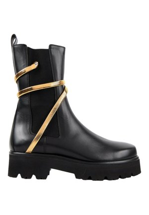 Bottine noire en cuir avec semelle épaisse et sangle dorée en forme de serpent enroulée autour de la tige.