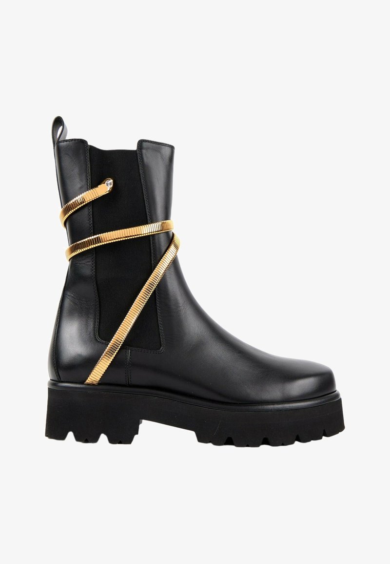 Bottine noire en cuir avec semelle épaisse et sangle dorée en forme de serpent enroulée autour de la tige.