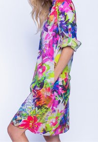 Bunt gemustertes Blumenkleid mit einer Vielzahl hellen Farbtönen, lockerem Schnitt, langen Ärmeln mit aufgerollten Manschetten und Seitenfächern. Aus leichtem Stoff hergestellt.