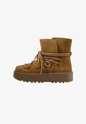 Braune Wildleder-Stiefeletten mit einer dicken, strukturierten Plateausohle und einer Schnürung auf der Vorderseite. Sie verfügen über einen gefalteten oberen Rand und dekorative Seilakzente.