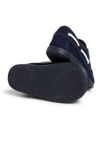 Marinefarbene Leinenschlüpfschuhe mit weißen Schnürsenkeln, ausgestattet mit einer strukturierten Gummisohle und einem gepolsterten Kragen für Komfort. Die Sohle ist schwarz mit minimalem Verschleiß.