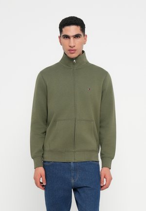 Olive green zip-up sweatshirt with high collar, front pockets, ribbed cuffs, and a small logo on the chest. Fabric appears soft and smooth.