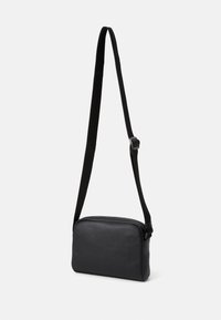 Borsa a tracolla nera con texture, chiusura a zip, tracolla in tessuto regolabile e forma rettangolare. Design minimalista, senza hardware visibile.