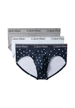 Tre par Calvin Klein herretrusser i grå, hvid og marineblå med hvide halvmånemønstre, hver med et mærket elastik i taljen.