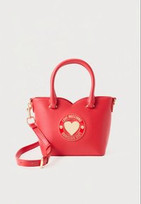 Borsa a mano in pelle rossa con doppi manici, tracolla staccabile e emblema a forma di cuore dorato con scritta "Love Moschino" al centro frontale.