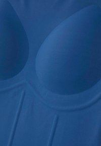 Tessuto in blu con coppe moldate e imbottite e design senza cuciture. Superficie liscia con una sottile lucentezza e senza dettagli di cucitura visibili.