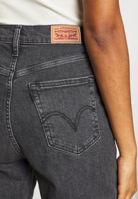 Svarta denimjeans med en distinkt rundad bakfickdesign. Har en Levi Strauss & Co. patch vid midjan.