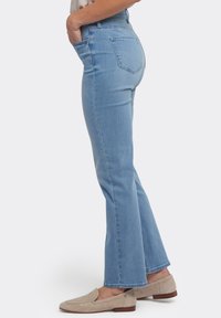 Ljusblå högmidjade jeans med utsvängda ben, femficksdesign och slät textur. Bärs med beige loafers.