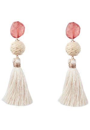 Clous facettés roses avec boule tissée beige et longues boucles d’oreilles à pampilles couleur crème sur fond blanc.