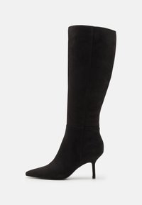 Bottes hautes jusqu'au genou en daim noir avec un bout pointu et un talon fin. Texture lisse avec un design structuré, sans fermetures ni ornements visibles.