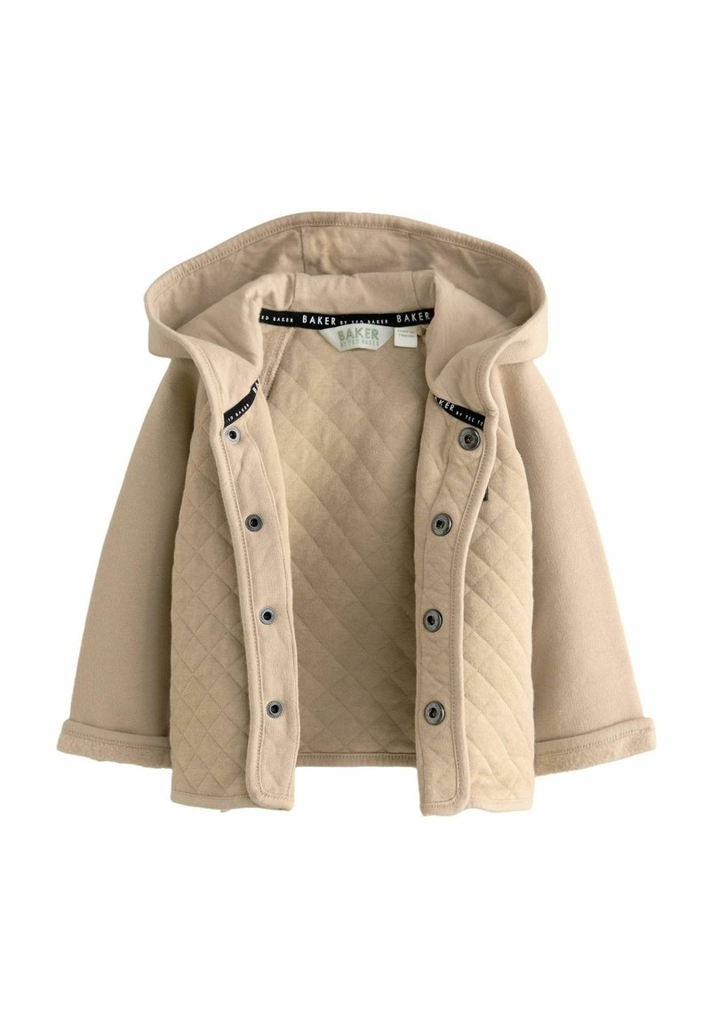 Beige vuorattu takki hupulla, jossa on nappikiinnitys, pehmeää kangasta ja erottuva sisävuori. Tiheä tekstuuri olkapäissä.