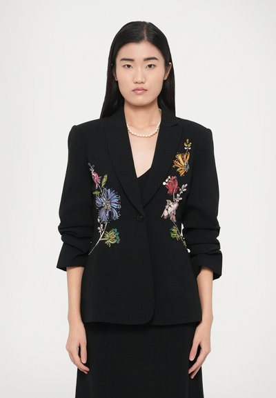 Blazer noir avec broderie florale colorée, épaules structurées et fermeture à un bouton. Tissu lisse avec une coupe ajustée.