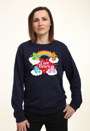 Marineblå sweatshirt med et farverigt Care Bears grafik, der inkluderer en regnbue, fire bamser på skyer og tekst i hjerteform.
