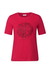 T-shirt en coton rouge à manches courtes et col rond, présentant un motif graphique circulaire en texte noir et gris sur le devant.