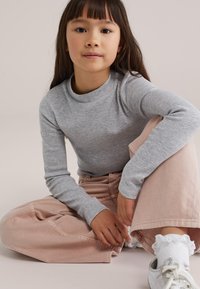 Hall pika varrukaga soonikkoes pluus koos heleda roosa laiade pükstega. Komplekti kuuluvad valged pitsist sokid ja metallik hõbedased jalanõud.