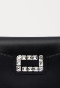 Borsa a tracolla nera in satin con una chiusura rettangolare decorata con strass. Texture liscia, forma strutturata e design elegante.