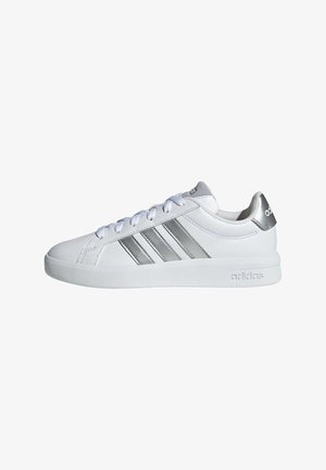 White Adidas sneaker with silver stripes, white laces, and silver heel tab, viewed from the outer side against a white background.