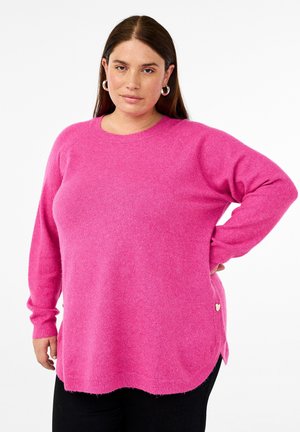 Pink knitted sweater with a round neckline, long sleeves, side slits, and a small heart accent on the bottom left. Soft texture.