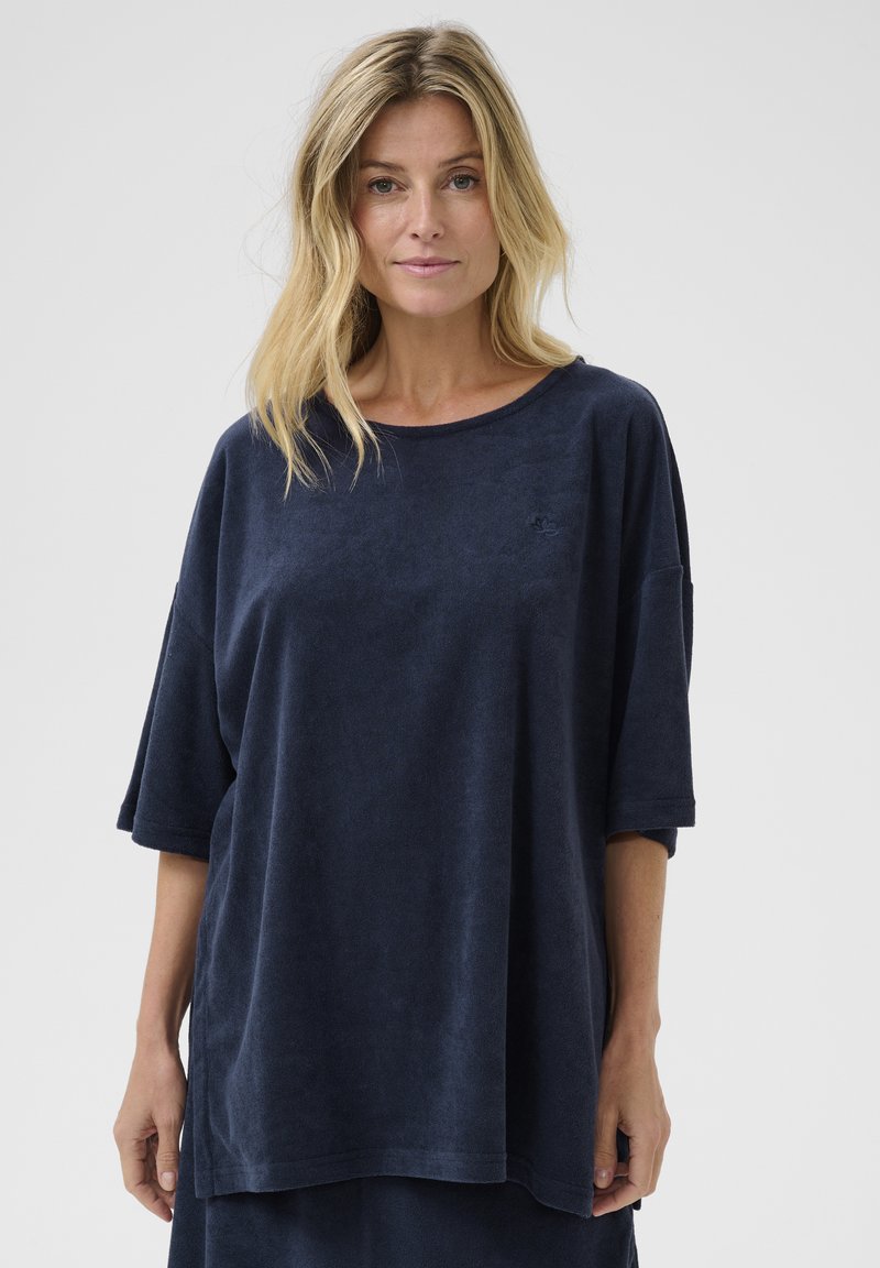 Sötétkék, oversized, puha törölköző anyagból készült póló, kerek nyakkivágással és rövid ujjakkal, finom hímzett logó részlettel.