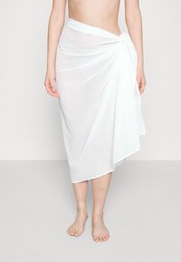 Falda blanca y transparente hecha de tela ligera, con un diseño drapeado y un detalle anudado en la cintura.