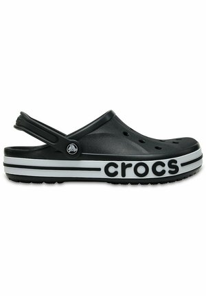 Sort-hvid slip-on Crocs klods med ventilationshuller, justerbar hælrem og dristig 'crocs'-branding på sålen.